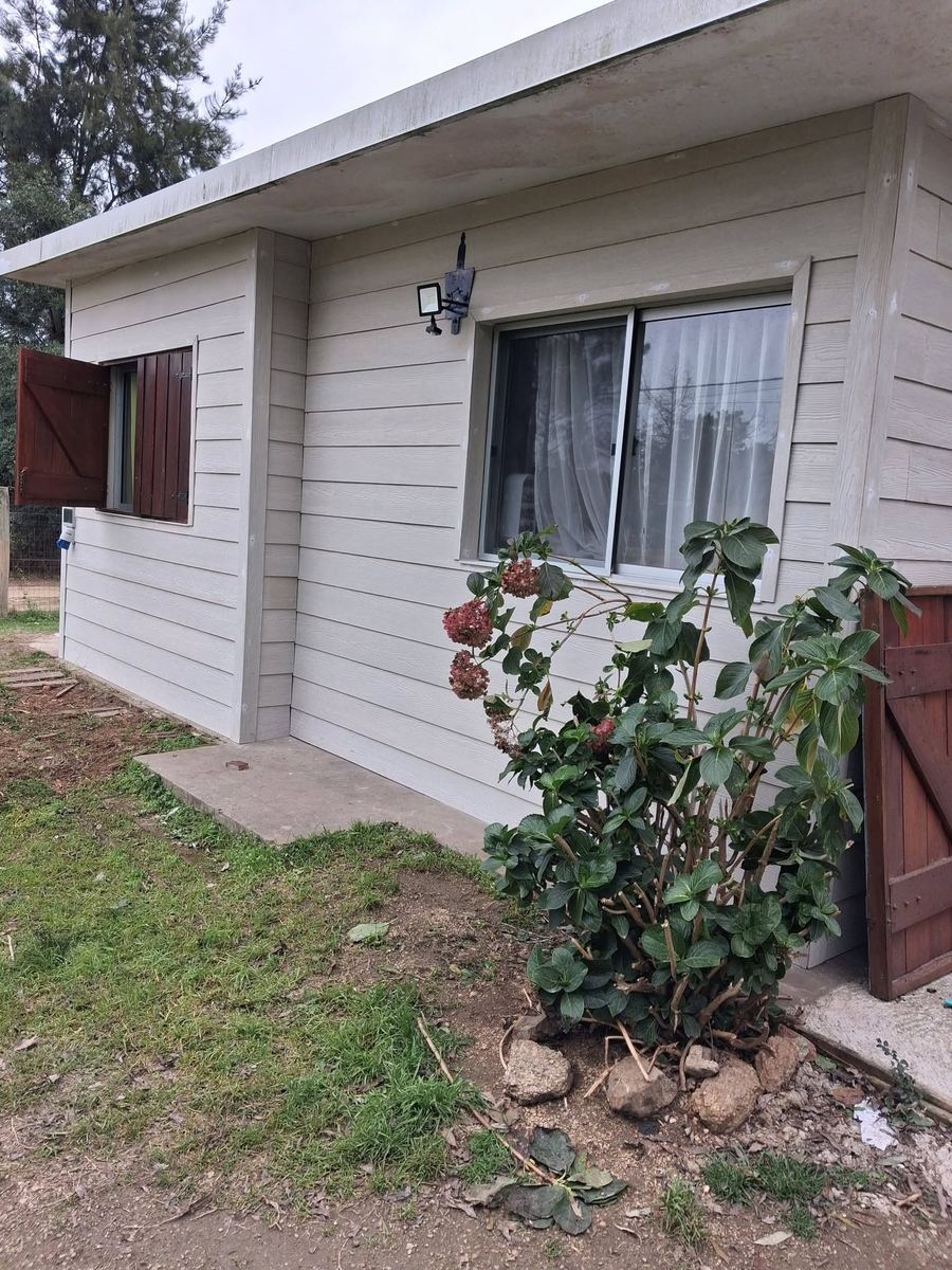 Fachada terminada con siding claro y aberturas nuevas